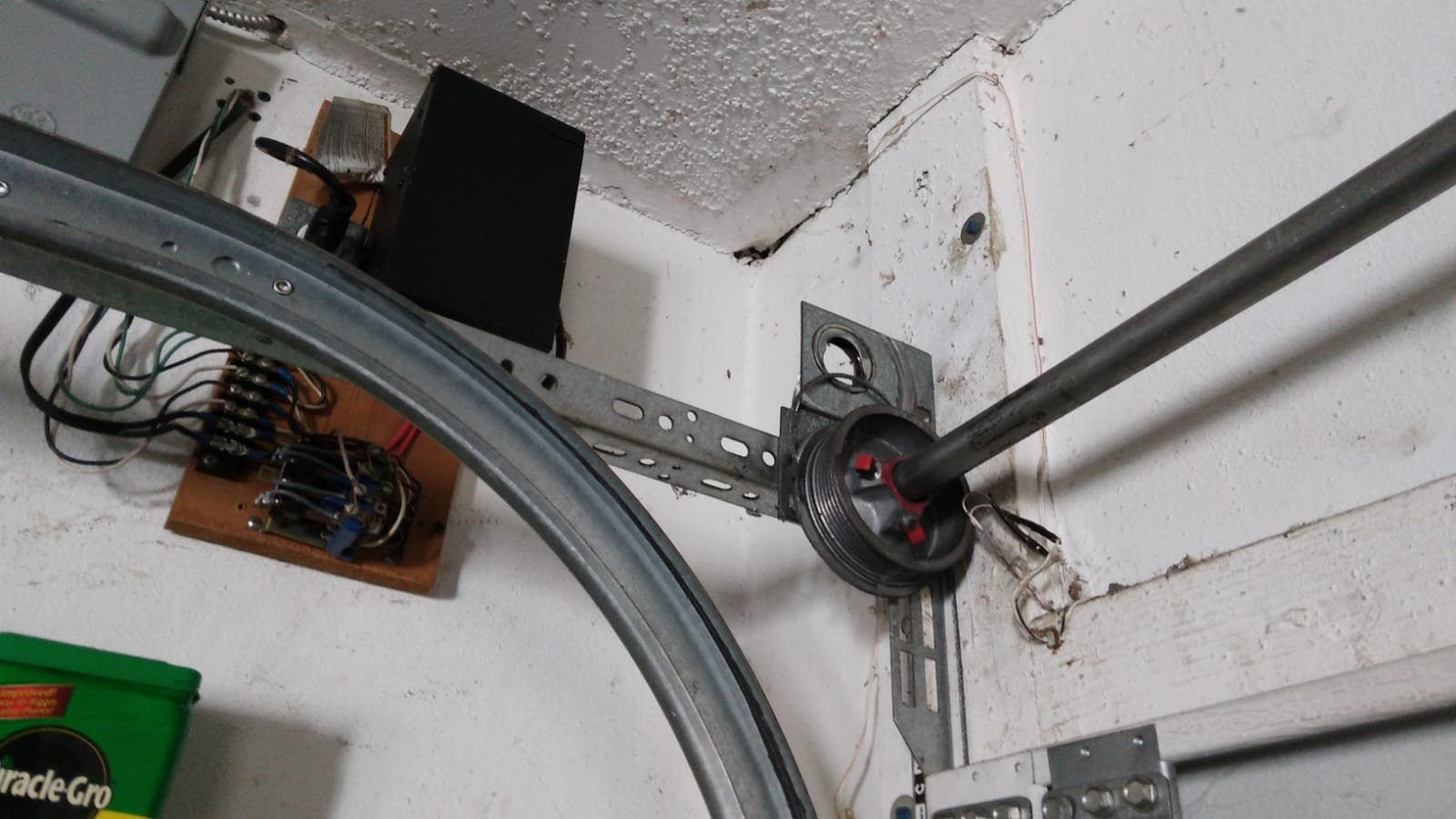 Garage door track, torsion shaft and cable-drum hardware near the ceiling.
